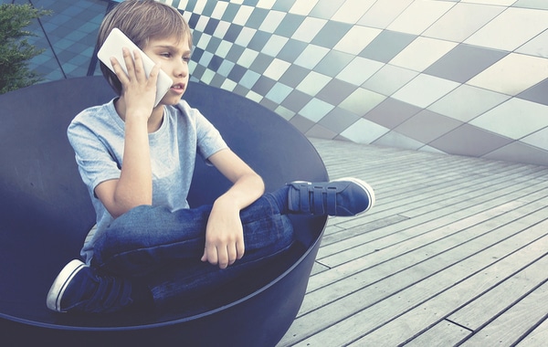 Boy on mobile phone sitting  in blue chair