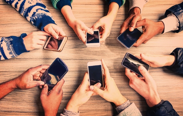 Group of people sitting around a table using their mobile phones.