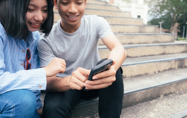 Two teens looking at a mobile phone together.