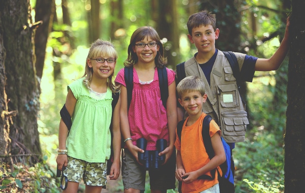 Group of kids with backpacks in a forest setting.