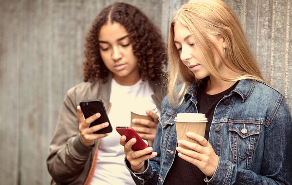 Two teenage girls using their mobile phones.