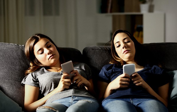 Two teenage girls using their phones.