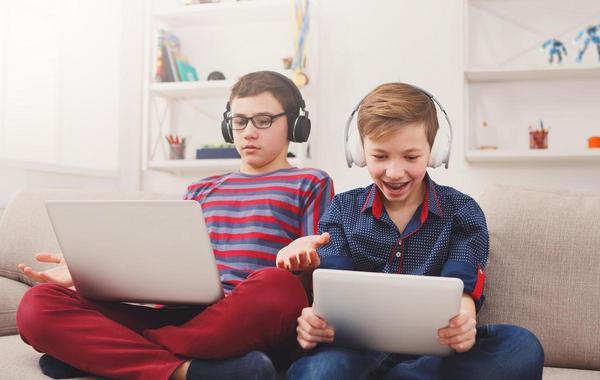 Two teens sitting in front of their laptops or tablets.