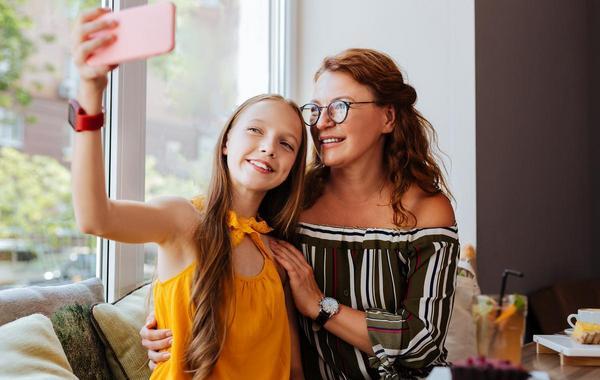Teen girl taking a photo with mom.