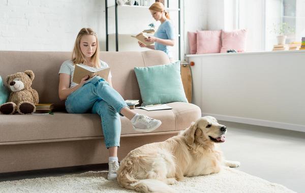 Teen sitting on a couch reading a book.