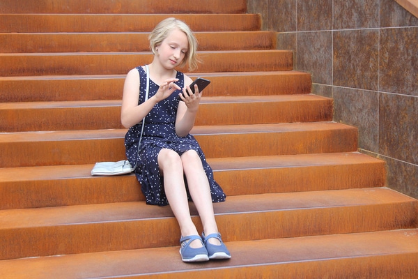 Young girl sitting on steps using a mobile phone.