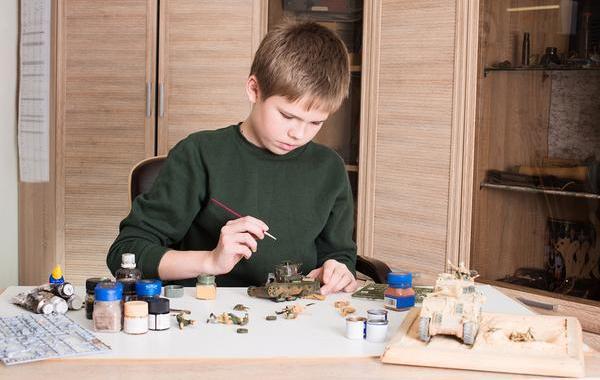 Young teenage boy painting a model tank.