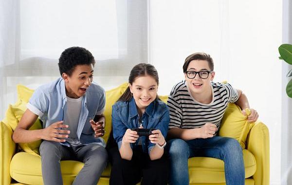 Three teens sitting on a couch with a game controller.