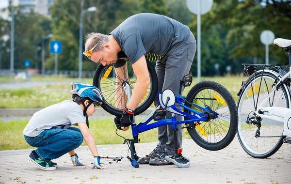 Dad helping his teen son fix a tire on his bicycle.