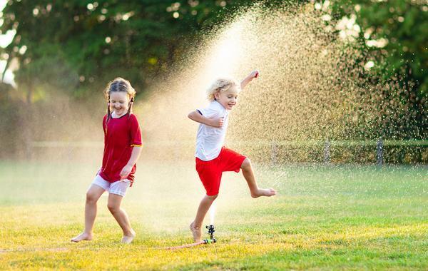 Kids playing outside with a sprinkler.