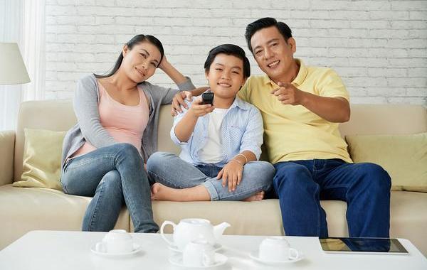 Happy family sitting on a couch watching tv.