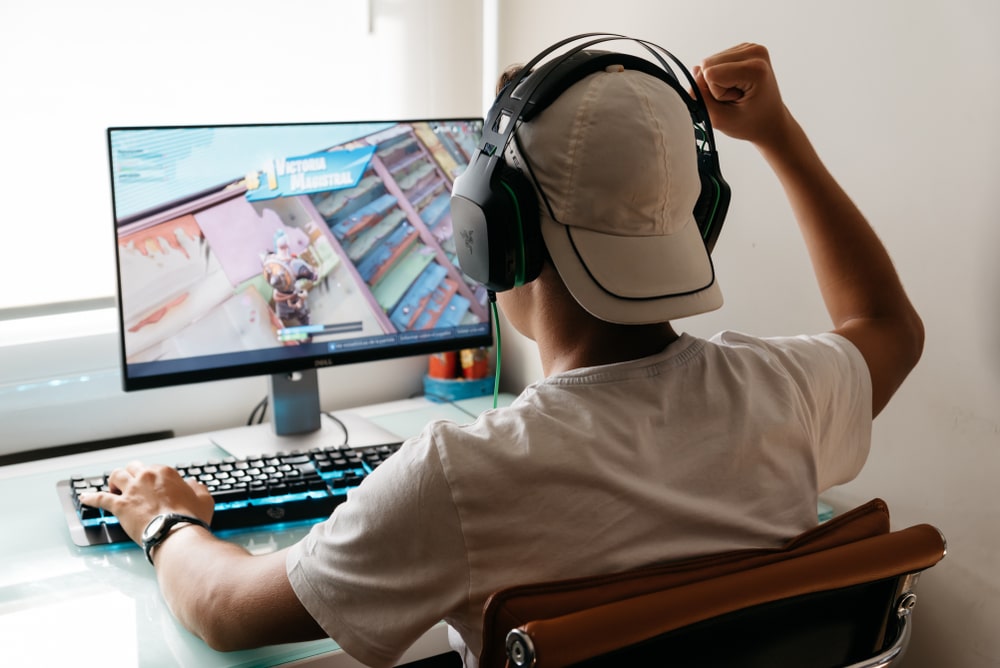 A teen plays Fortnite on his computer; illustration of the game’s T for Teen rating