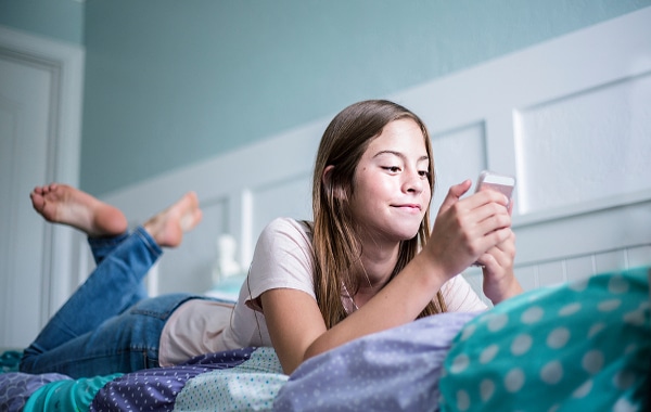 Young teen lying down looking at her phone.