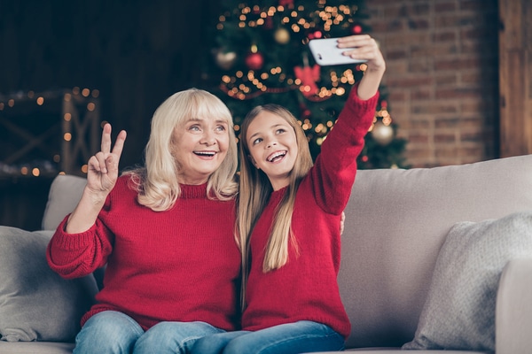 Grandmother and granddaughter in red sweaters taking a selfie.
