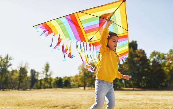 Girl flying a colorful kite.