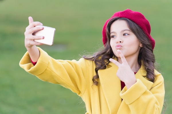 Young teen taking a selfie while giving the peace sign.