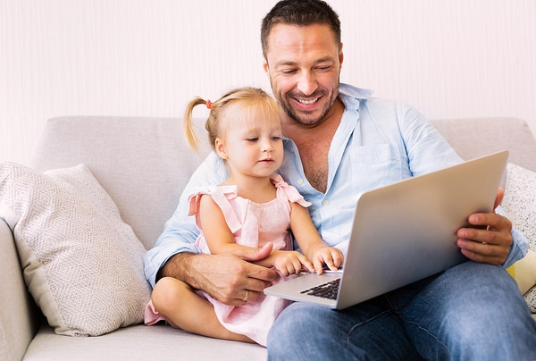 Father sitting with his daughter in front of a laptop.