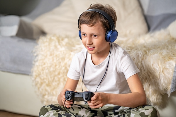 Young teen wearing headphones and holding a game controller.