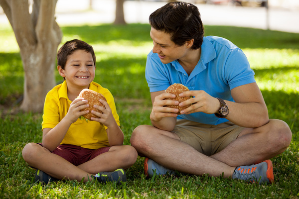 Parent and child eating hamburgers.