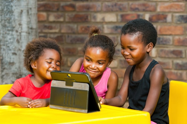 Three children looking at a tablet together