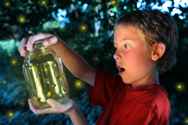 Child looking at fireflies in a glass bottle.