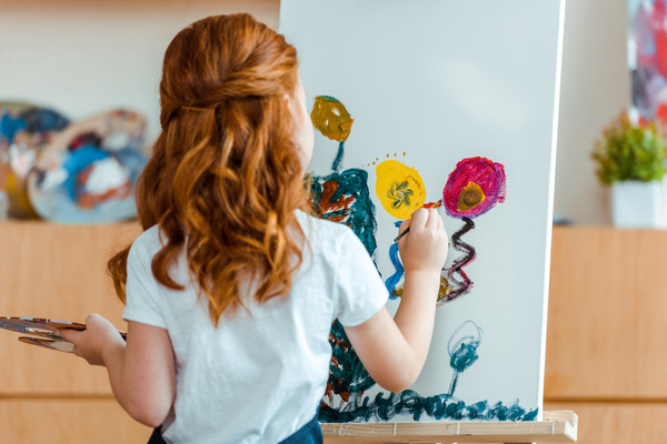 Child painting flowers on a canvas.