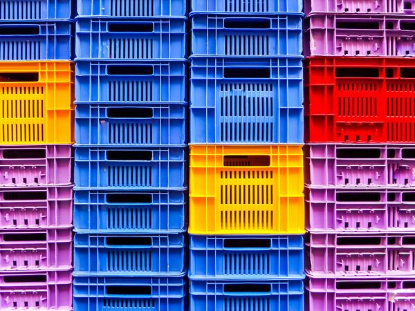Stacks of blue, yellow, purple and red milk crates.